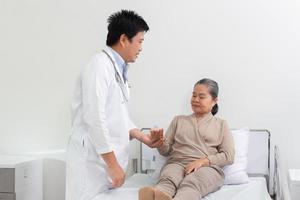 asiatique Masculin médecin expliquant médicament à personnes âgées femelle patient dans hôpital. photo