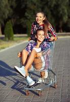 deux content magnifique adolescent les filles conduite achats Chariot en plein air photo