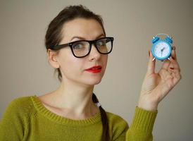 peu bleu alarme l'horloge dans le mains de pensif Jeune femme photo