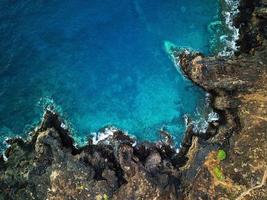 Haut vue de une déserté côte. rocheux rive de le île de tenerife. aérien drone métrage de mer vagues atteindre rive photo