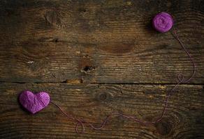 violet cœur avec une Balle de fil sur sur vieux minable en bois Contexte photo