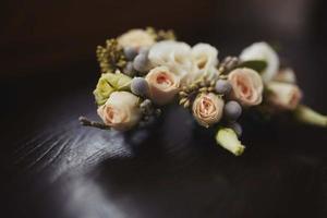 gros plan sur les fleurs de la boutonnière du marié avec des roses blanches, du vert et de la verdure. notion de mariage. belles fleurs vivantes photo