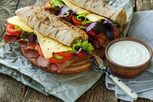 savoureux des sandwichs avec jambon, fromage, laitue, tomate et une bol de acide crème photo