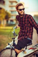 homme dans des lunettes de soleil équitation une bicyclette sur ville rue photo