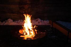 bois de chauffage des brûlures dans le centre de une rond métal barbecue tableau. photo