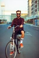 homme dans des lunettes de soleil équitation une bicyclette sur ville rue photo