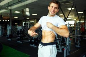athlétique homme montrant abdominal muscles dans Gym photo