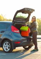 souriant caucasien femme en mettant sa achats Sacs dans le voiture tronc photo