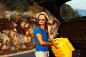 Jeune femme chargement bagage dans le retour de voiture photo