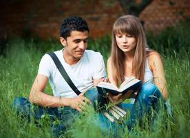 deux élèves en train d'étudier dans parc sur herbe avec livre en plein air photo