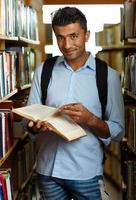 étudiant en train de lire livre entre le étagères dans le bibliothèque photo