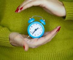 peu bleu alarme l'horloge dans le mains de pensif Jeune femme photo