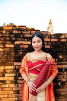 magnifique thaïlandais fille dans traditionnel robe costume rouge parapluie comme thaïlandais temple où est le Publique lieu, thaïlandais femme dans traditionnel costume de Thaïlande. photo