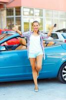 Jeune émotif femme permanent près une convertible avec le clés dans sa main photo
