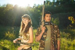 blanc fille et un arabe homme dans camouflage avec une arme dans le mains de en plein air photo