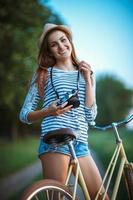 charmant Jeune femme dans une chapeau avec une vélo en plein air photo