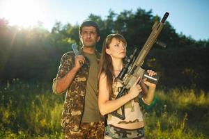 blanc fille et un arabe homme dans camouflage avec une arme dans le mains de en plein air photo