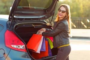 femme en mettant sa achats Sacs dans le voiture tronc photo