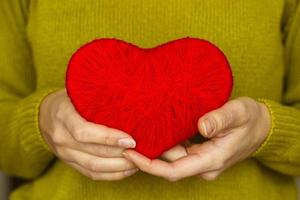 fermer sur rouge cœur fabriqué de la laine dans main de femme photo