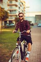 homme dans des lunettes de soleil équitation une bicyclette sur ville rue photo