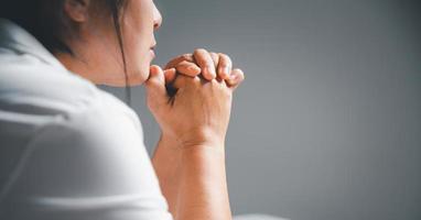 femme a genou et prier dans moderne maison à le coucher du soleil temps. femelle catholique prière culte à Dieu souhait une mieux la vie dans Accueil à Aube avec croyez foi. concept de fidèles a genou. photo