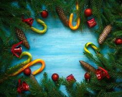 Noël frontière avec sapin arbre branches, cônes, Noël décorations et bonbons canne sur bleu en bois planches photo