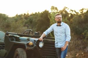 Jeune élégant homme avec des lunettes et arc attacher près le démodé suv photo