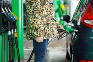 femme remplit essence dans sa voiture à une gaz station dans hiver photo