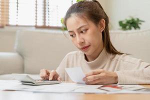 financier devoir asiatique Jeune femme, fille séance souffrir, stressé et confus par calculer frais de facture d'achat ou facture, avoir non argent à payer, hypothèque ou prêt. dette, la faillite ou la faillite concept. photo