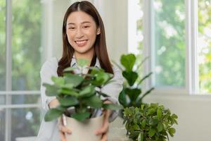 content asiatique Jeune femme, client reçu, déballer paquet carton ouvert parcelle dans papier carton boîte, en portant céramique plante pot. en mouvement, en train de préparer dans Nouveau loger, déménagement. en ligne magasin livraison à maison. photo