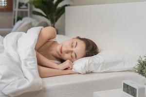 sucré rêves, attrayant sourire jolie asiatique Jeune femme, fille en train de dormir dans confortable lit mensonge sur doux oreiller repos, en gardant yeux fermé tandis que avec couvert couverture dans confortable blanc lit dans le Matin. photo