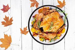 rôti dinde garni avec canneberges sur une rustique style table décoré l'automne feuille. action de grâces journée. cuit poulet. Haut vue photo