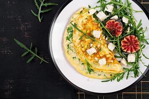 omelette avec feta fromage, persil et salade avec figues, Roquette sur blanc plaque. frittata - italien omelette. Haut voir. plat poser. photo