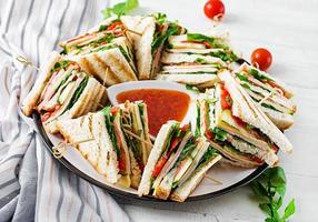 club sandwich avec jambon, tomate, concombre, fromage, et Roquette sur en bois Contexte. photo