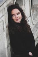 magnifique Jeune femme avec brunette frisé cheveux, portrait dans œil des lunettes profiter le Soleil dans le ville. photo