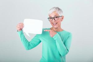 content mature femme dans plaine bleu longue manche T-shirt en portant vide discours bulle isolé sur Contexte. femme montrant signe discours bulle bannière à la recherche content et montrer du doigt sa doigt sur il photo