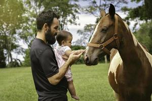 père et peu fille émouvant cheval. photo