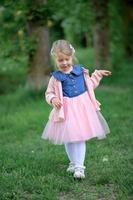 une peu fille 3 ans vieux des promenades dans le parc dans une robe et une rose chandail. photo
