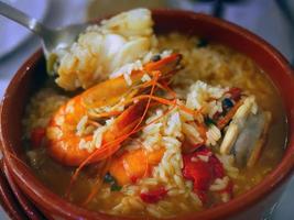 sélectif se concentrer, proche en haut authentique traditionnel Portugais Fruit de mer soupe avec riz, arroz de marisco dans rouge bol photo