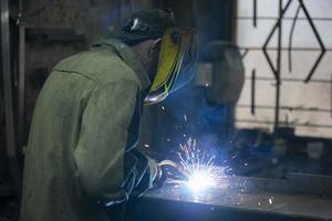 une soudeur travaux avec métal dans une usine magasin. photo