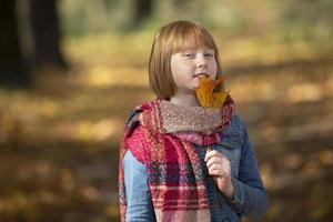 content roux fille avec érable feuille dans l'automne parc. photo