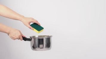 main d'homme de nettoyage de pot sur fond blanc nettoyant le pot antiadhésif avec une éponge à vaisselle pratique de couleur jaune sur le côté doux et verte sur le côté dur pour l'hygiène après la cuisson. marmite électrique