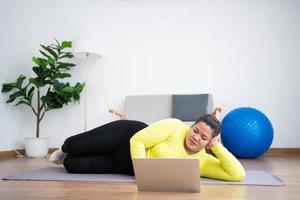 portrait plus taille femme utilisateur ordinateur portable pour rejoindre un cours de fitness pour faire de l'exercice avec un ballon de fitness dans la salle de gym à domicile. concept de technologie et de communication, de soins de santé et de perte de poids. photo