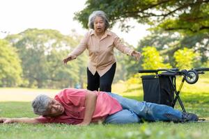 homme senior asiatique tombant du fauteuil roulant sur le sol couché après avoir essayé de pousser le fauteuil roulant vers l'avant et pleurant de douleur et demandant de l'aide à quelqu'un. concept d'assurance vieillesse et de soins de santé photo