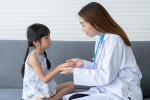 femme asiatique médecin pédiatre tenir stéthoscope pour examen une petite fille patiente et sacré poumons cardiaques d'enfant, bon médecin de famille visitant un enfant à la maison, soins de santé et médecine pour le concept de l'enfance. photo