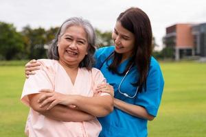 un soignant ou une infirmière asiatique prudente tient la main du patient et l'encourage dans un jardin. concept de retraite heureuse avec les soins d'un soignant et l'épargne et l'assurance maladie senior. photo