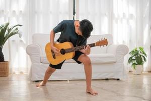 portrait de une asiatique content souriant garçon ayant amusement en jouant guitare la musique concept, des gamins la musique école. Roche concert, la musique pour des gamins et les tout-petits concept photo