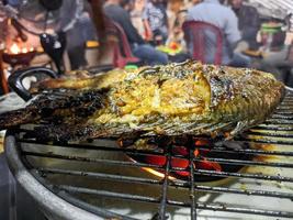 une proche en haut de poisson étant grillé avec une brûlant Feu. pour nourriture fond d'écran ou Contexte. non gens photo