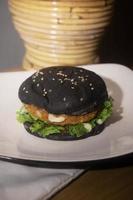 proche en haut photo de le ouvert noir Burger sur une blanc assiette est très adapté pour une vite nourriture menu