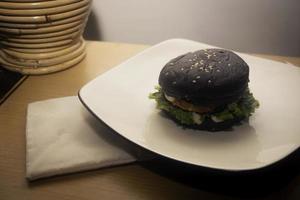 proche en haut photo de le ouvert noir Burger sur une blanc assiette est très adapté pour une vite nourriture menu